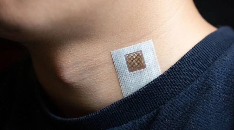 Parche electrónico adhesivo con sensor de rejilla metálica aplicado sobre el cuello de una persona.