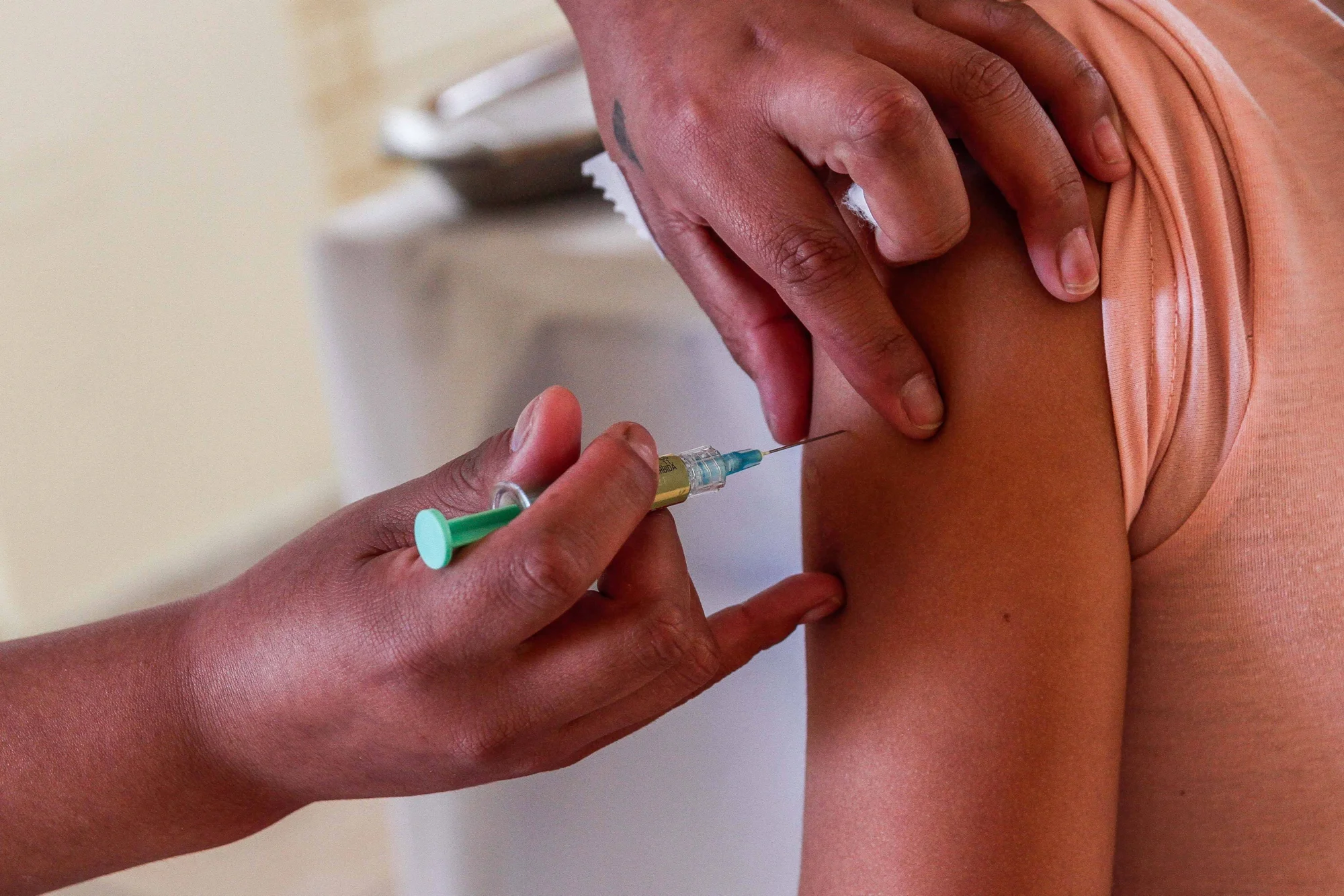 Un profesional de salud aplica una inyección con jeringa en el brazo de una persona.