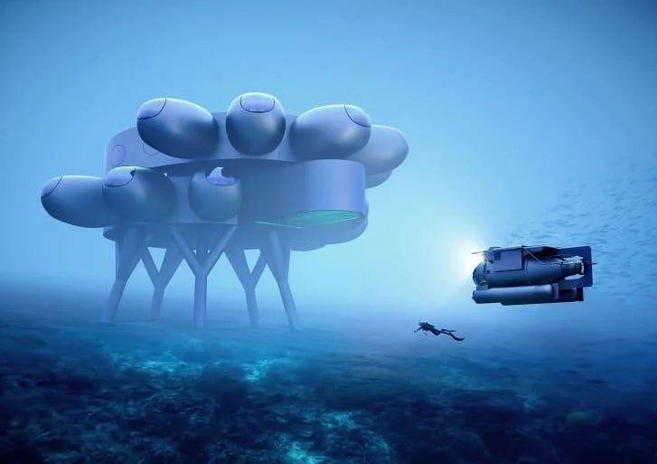 Render de una estación submarina futurista con módulos esféricos sobre pilotes, un buzo y un submarino pequeño explorando el fondo marino.