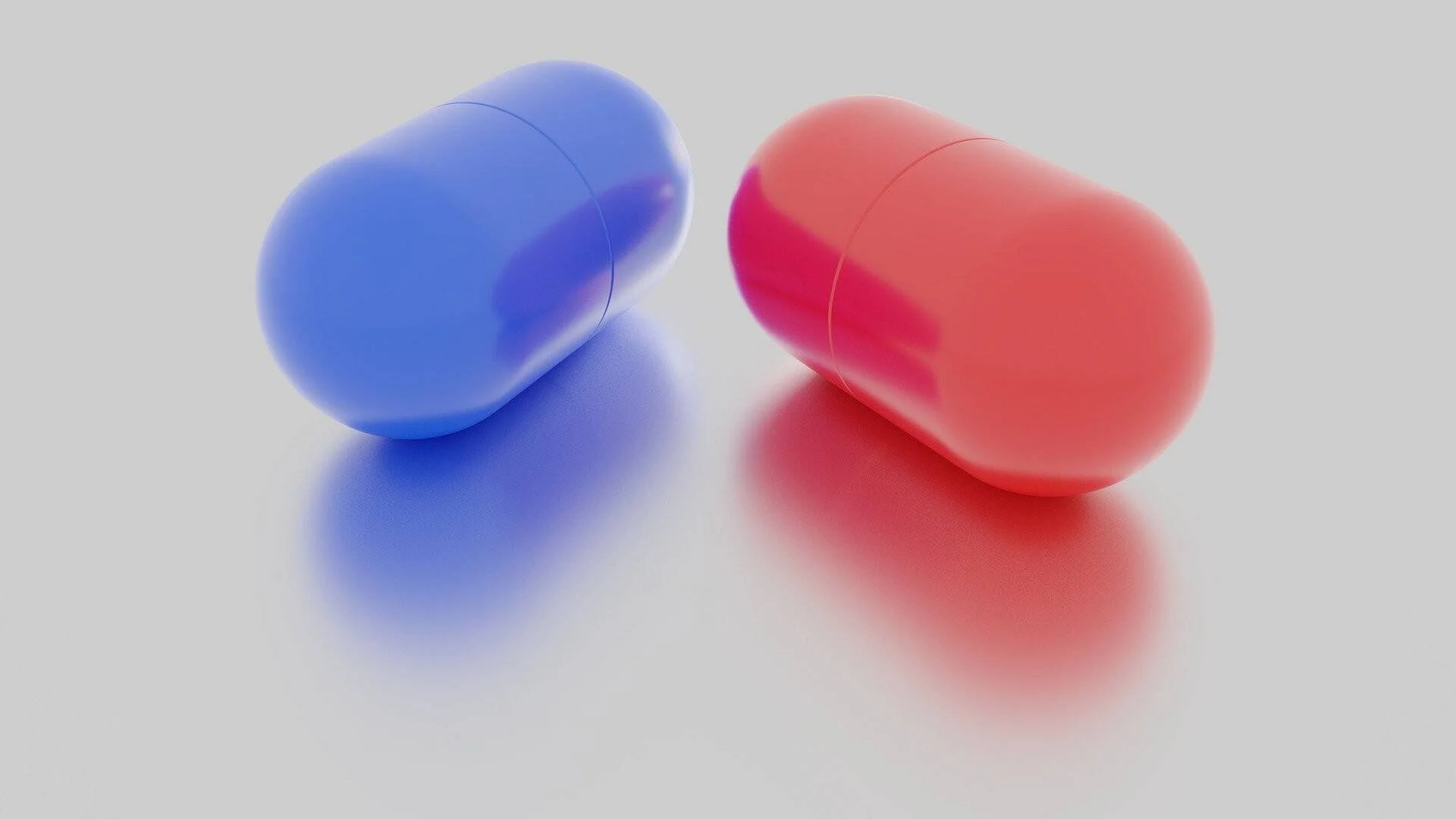 Dos cápsulas de medicamento, una azul y una roja, sobre una superficie blanca con reflejo.