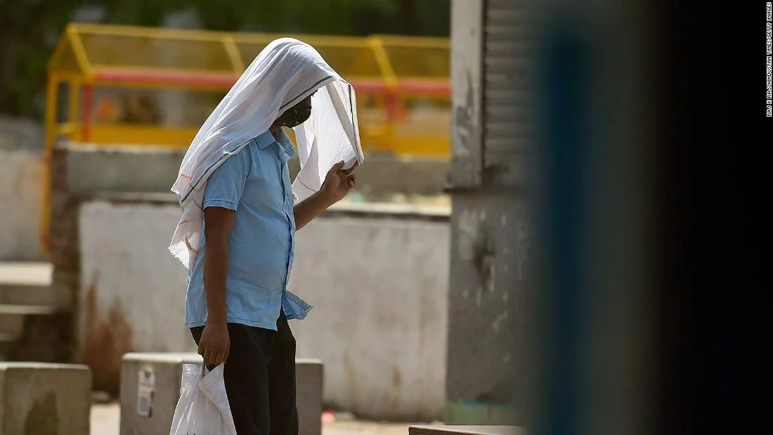 Una persona se cubre la cabeza y el rostro con una tela blanca para protegerse del intenso calor en la calle.