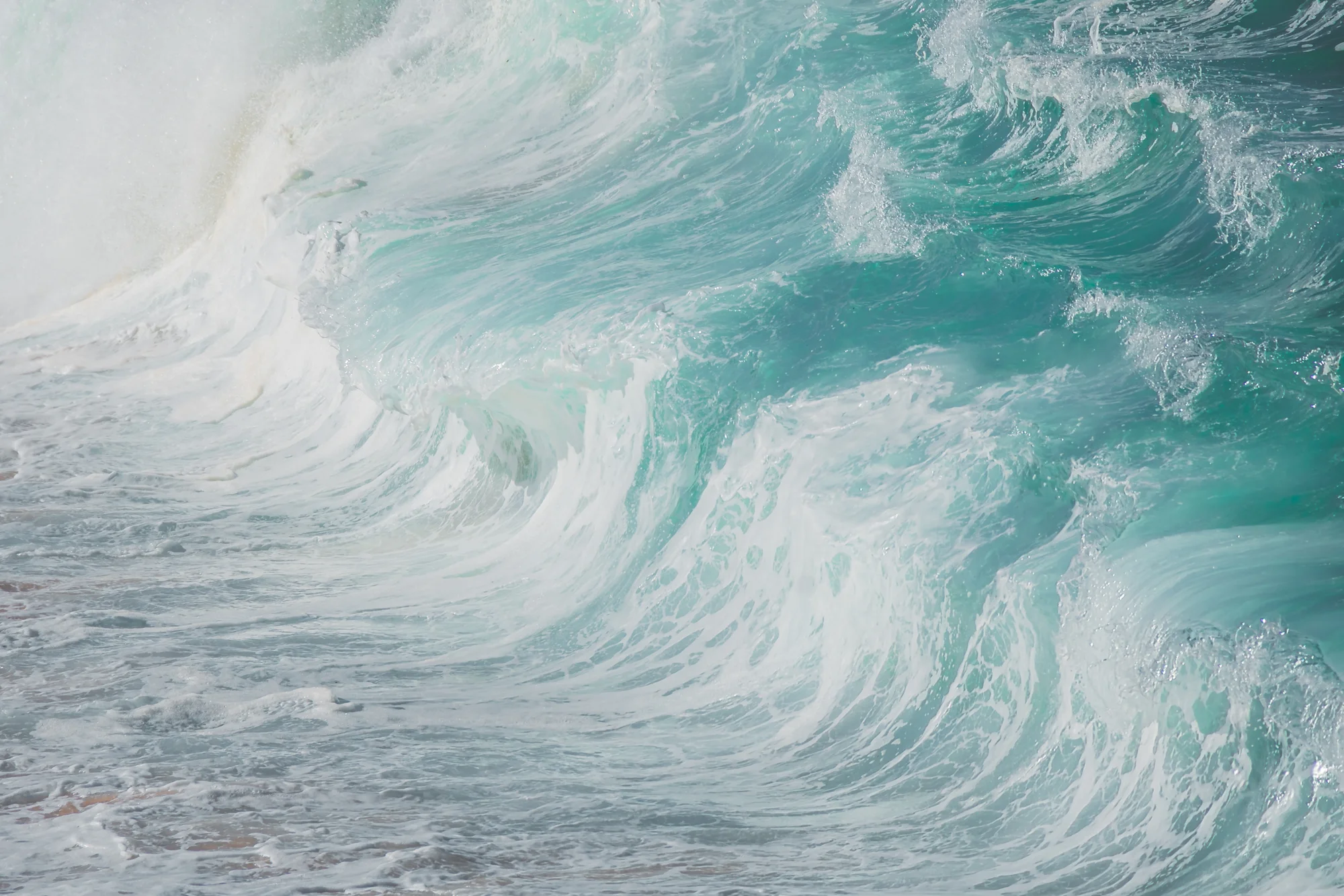 Grandes olas de agua turquesa con espuma blanca rompen con fuerza en el océano.
