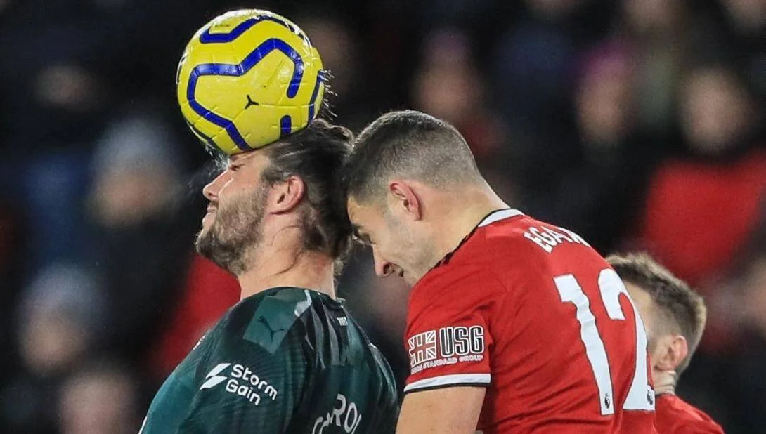 Dos jugadores de fútbol disputan un balón aéreo con la cabeza durante un partido de la Premier League.