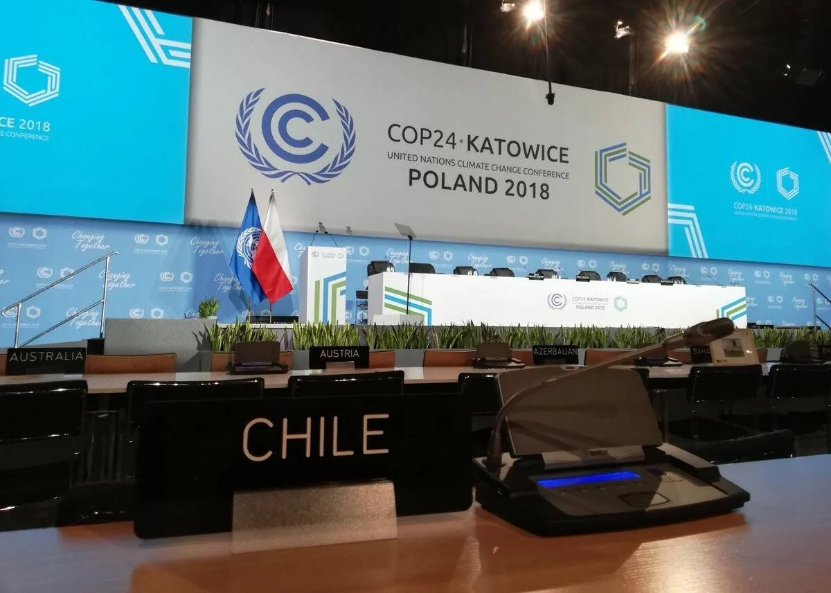 Sala plenaria vacía de la COP24 en Katowice, Polonia 2018, con el cartel de la ONU y el asiento de Chile en primer plano.