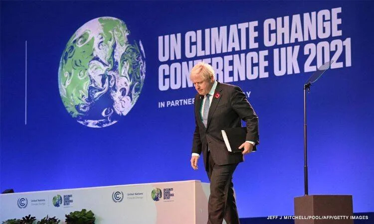 Un hombre de traje camina en el escenario de la Conferencia de Cambio Climático de la ONU UK 2021 (COP26).