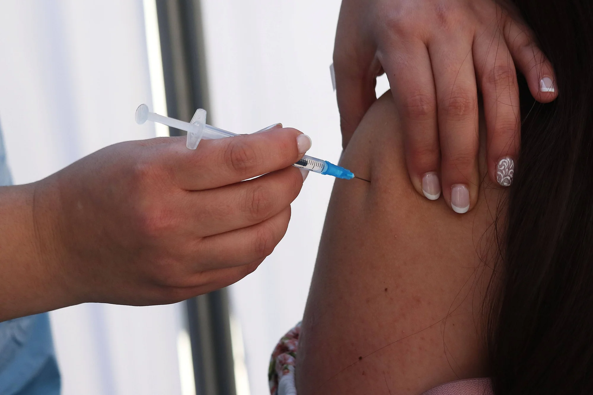 Un profesional de salud aplica una inyección con jeringa en el brazo de una persona.