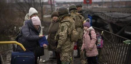 Soldados con equipo militar ayudan a civiles, incluidos niños con mochilas, a evacuar sobre un puente dañado.