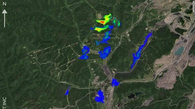 Imagen satelital con superposición de datos espectrales que muestra emisiones de metano en colores azul, verde y rojo sobre una zona minera boscosa.