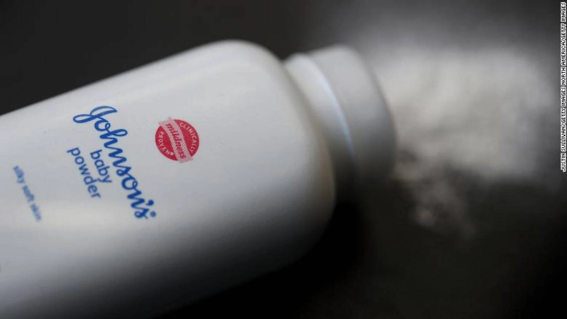 Frasco de Johnson's Baby Powder recostado, con polvo derramado visible alrededor.