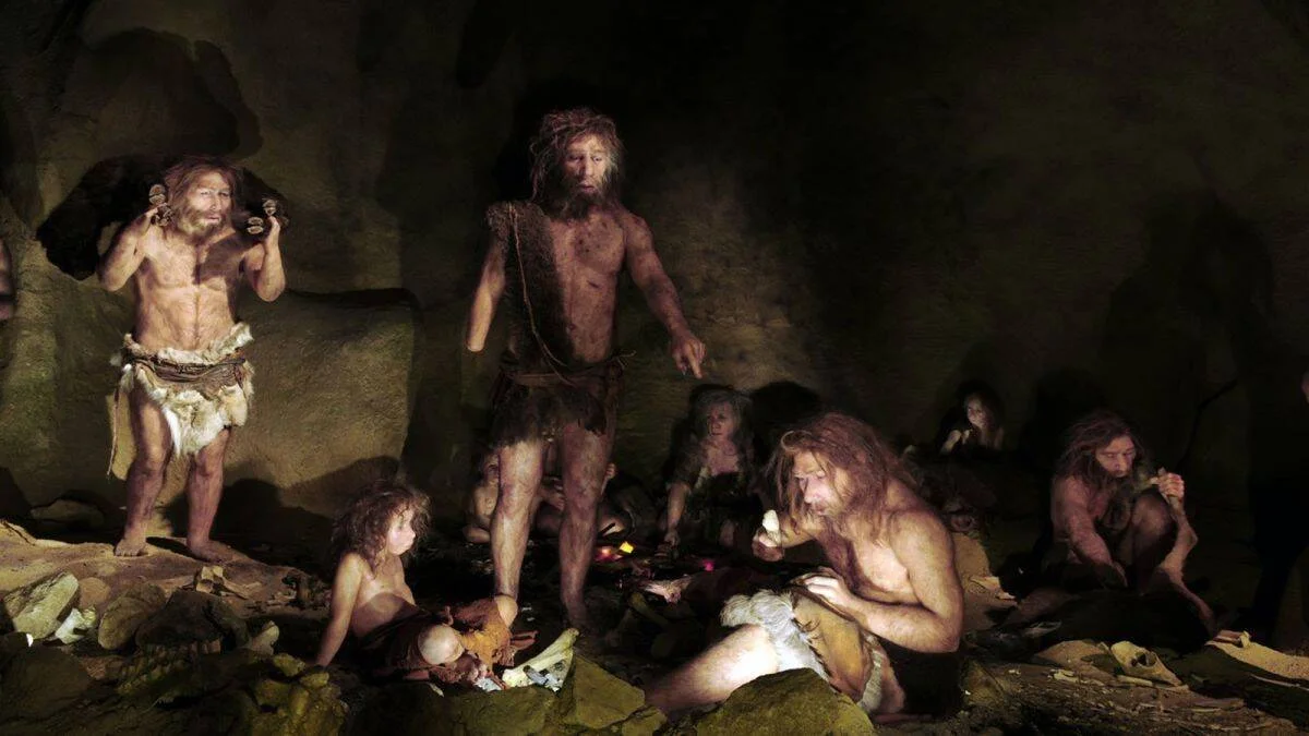 Recreación museística de un grupo de neandertales conviviendo en una cueva, con adultos y niños alrededor de una hoguera.
