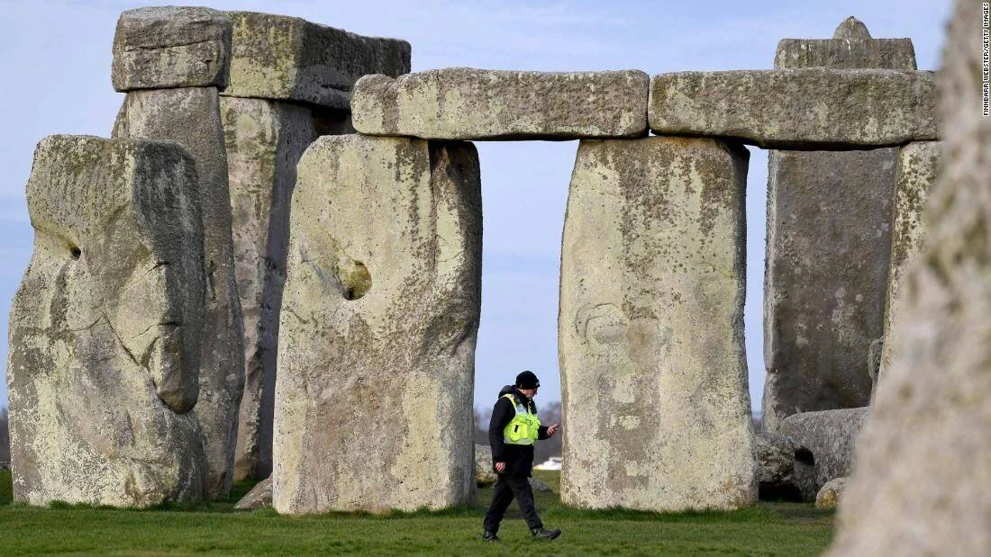Un agente con chaleco reflectante camina entre los megalitos de Stonehenge bajo un cielo despejado.