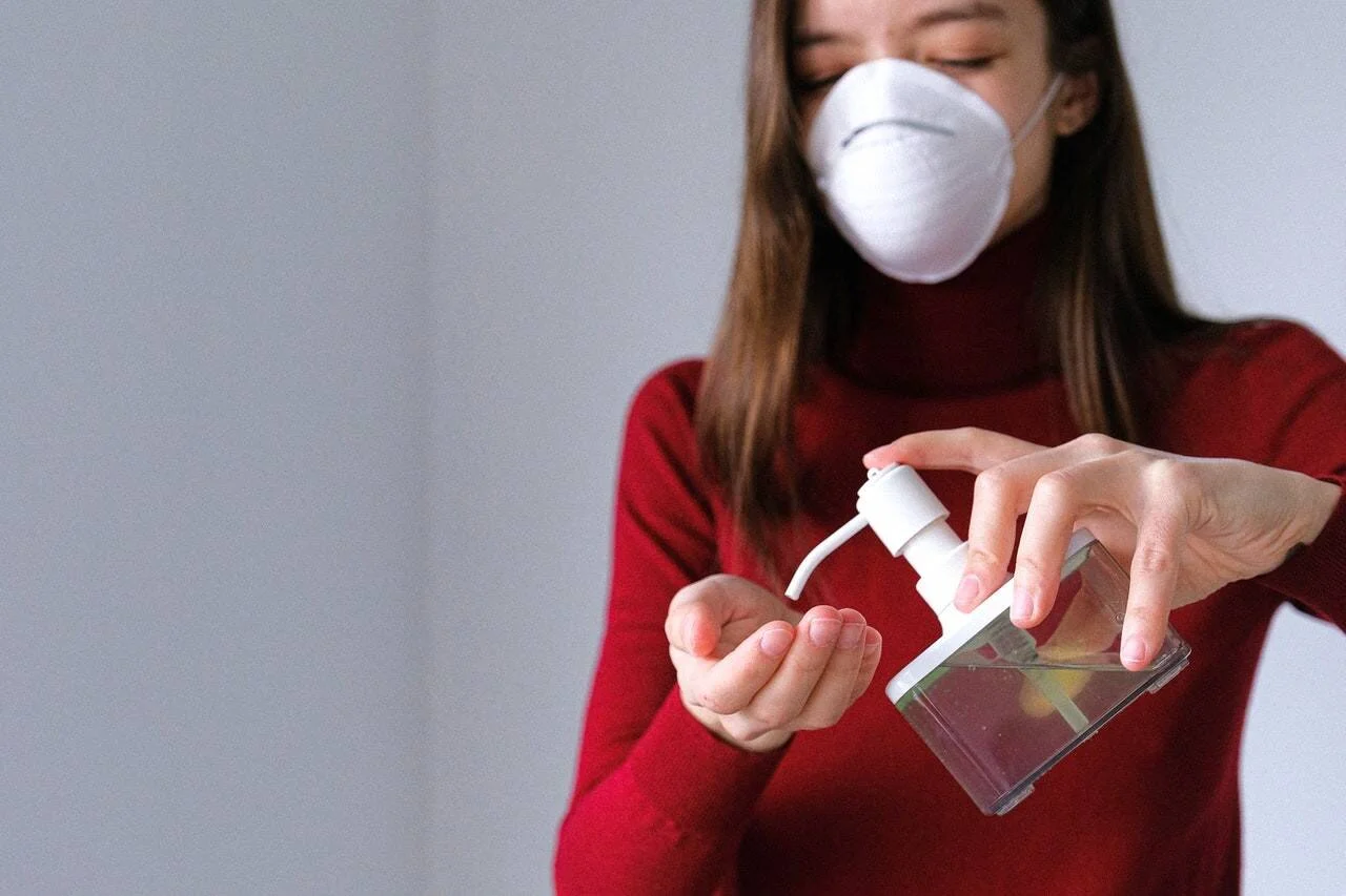 Mujer con mascarilla FFP2 aplica gel desinfectante en sus manos como medida de protección sanitaria.