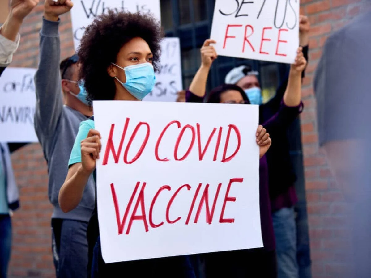 Manifestantes con mascarillas sostienen carteles que dicen 'No Covid Vaccine' y 'Set Us Free' en una protesta antigubernamental.