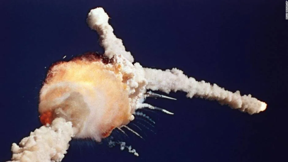 Gran bola de fuego y rastros de humo dispersos marcan la desintegración de un transbordador espacial en pleno vuelo.