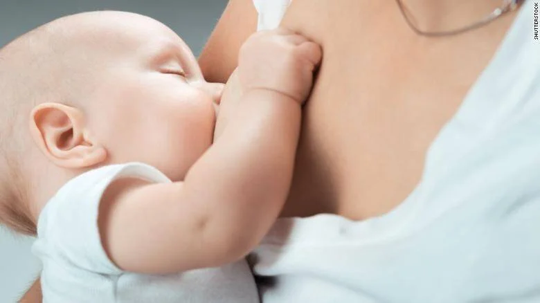 Bebé recién nacido amamantándose del pecho de su madre con los ojos cerrados.