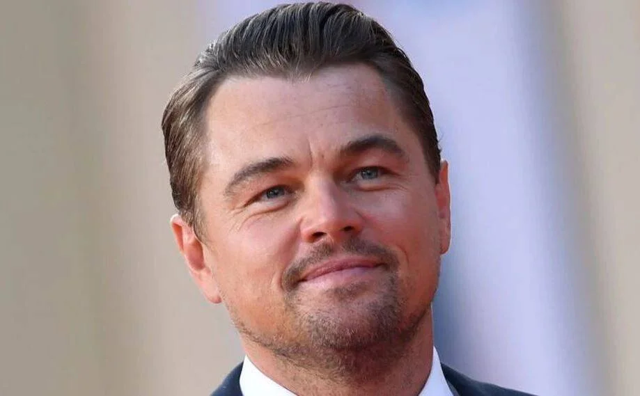 Hombre de mediana edad con cabello castaño peinado hacia atrás y barba corta, sonriendo levemente en un evento formal.