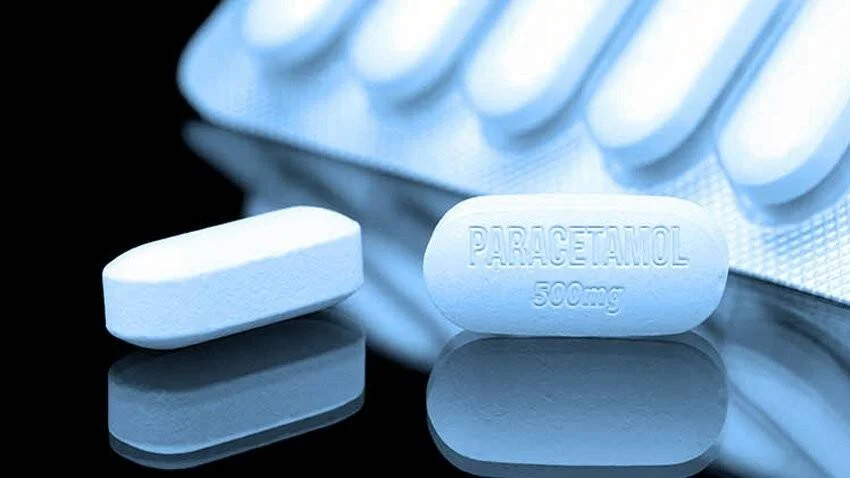 Dos comprimidos blancos de paracetamol 500 mg sobre superficie reflectante, con blíster al fondo.