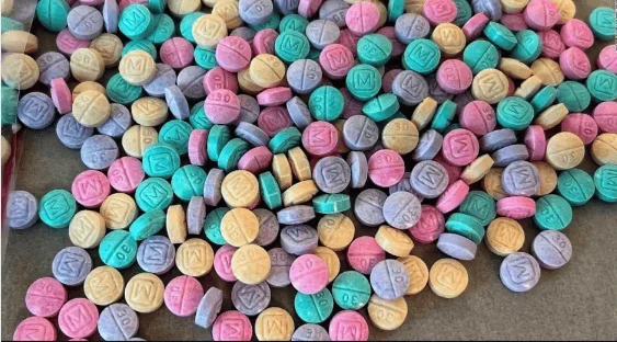 Gran cantidad de pastillas redondas de colores variados marcadas con 'M30', identificadas como fentanilo ilegal falsificado.