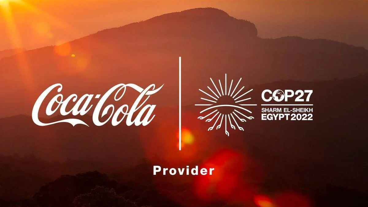 Logos de Coca-Cola y COP27 Sharm El-Sheikh Egypt 2022 con la leyenda 'Provider' sobre un fondo de montañas al atardecer.