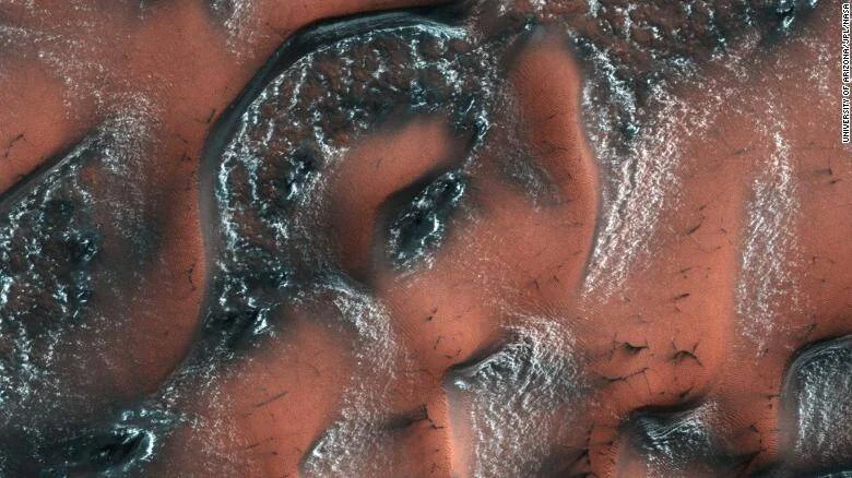 Dunas marcianas de color rojizo cubiertas con hielo de dióxido de carbono y marcas oscuras, captadas por la NASA.
