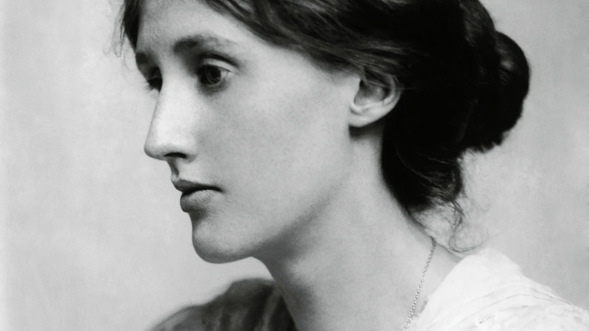 Fotografía histórica en blanco y negro de una mujer joven de perfil, con el cabello recogido y collar fino.