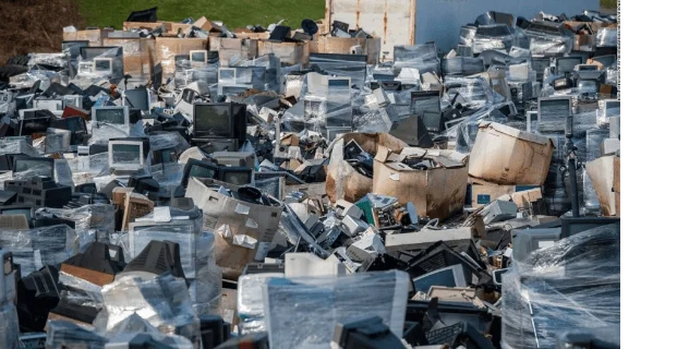 Gran acumulación de basura electrónica con monitores, televisores y aparatos obsoletos apilados en un vertedero a cielo abierto.