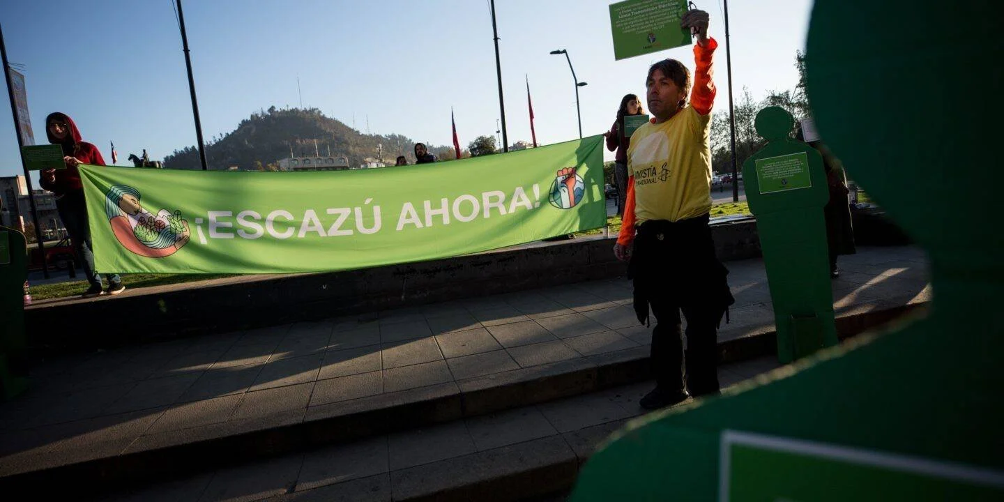 Activistas sostienen una pancarta verde con la consigna '¡Escazú Ahora!' durante una protesta en una plaza pública.