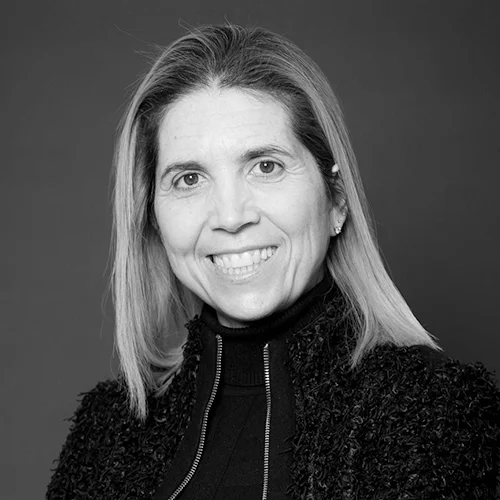 Mujer de cabello lacio y mediano sonríe a cámara en retrato profesional en blanco y negro.
