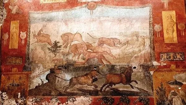Fresco romano en pared roja que representa una escena de caza con leones, ciervos y otros animales en movimiento.