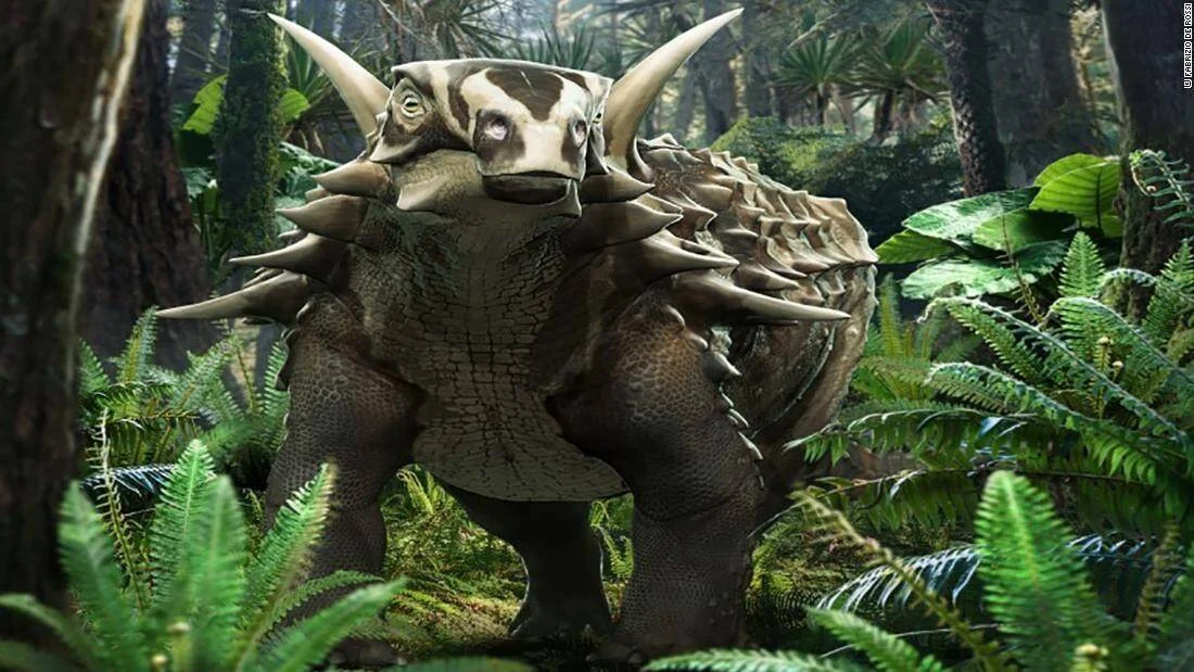 Ilustración artística de un dinosaurio anquilosaurio con cuernos y escamas, rodeado de helechos en un bosque prehistórico.