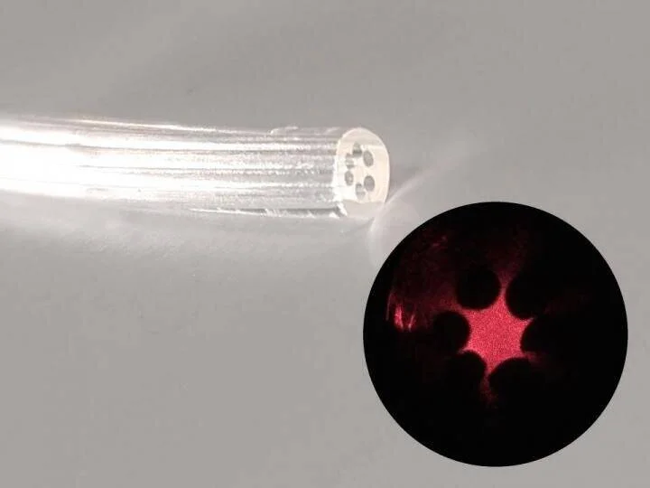 Extremo de una fibra óptica con microcanales internos, junto a un detalle ampliado que muestra luz roja propagándose por su interior.
