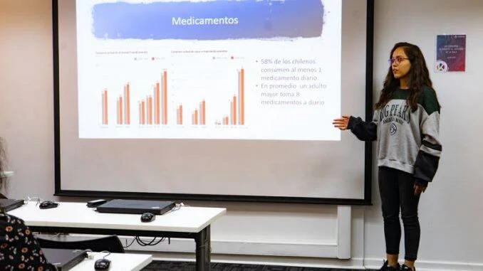 Joven expone ante una pantalla con datos sobre consumo de medicamentos en chilenos, mostrando gráficos de barras y estadísticas clave.