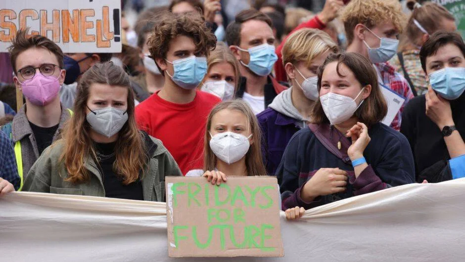 Grupo de jóvenes con mascarillas sostienen un cartel de 'Fridays for Future' en una manifestación por el clima.