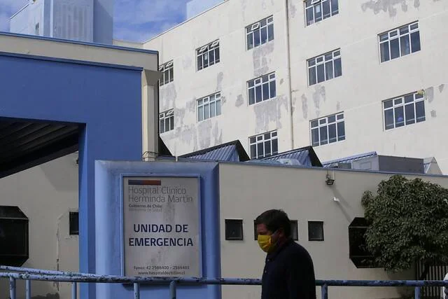 Persona con mascarilla pasa frente al letrero de la Unidad de Emergencia del Hospital Clínico Herminda Martín.