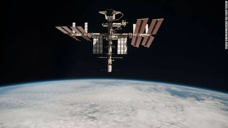 La Estación Espacial Internacional flota sobre la curva de la Tierra con sus paneles solares desplegados contra el espacio negro.