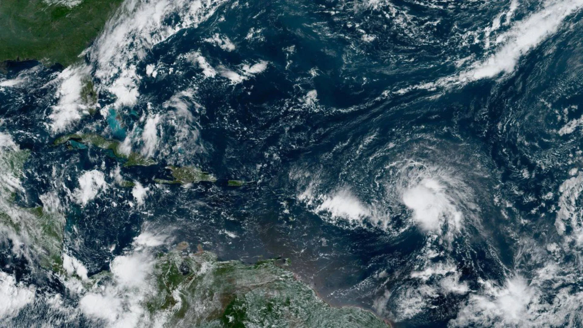 Vista satelital del Atlántico y el Caribe mostrando un sistema de nubes con rotación ciclónica en formación.