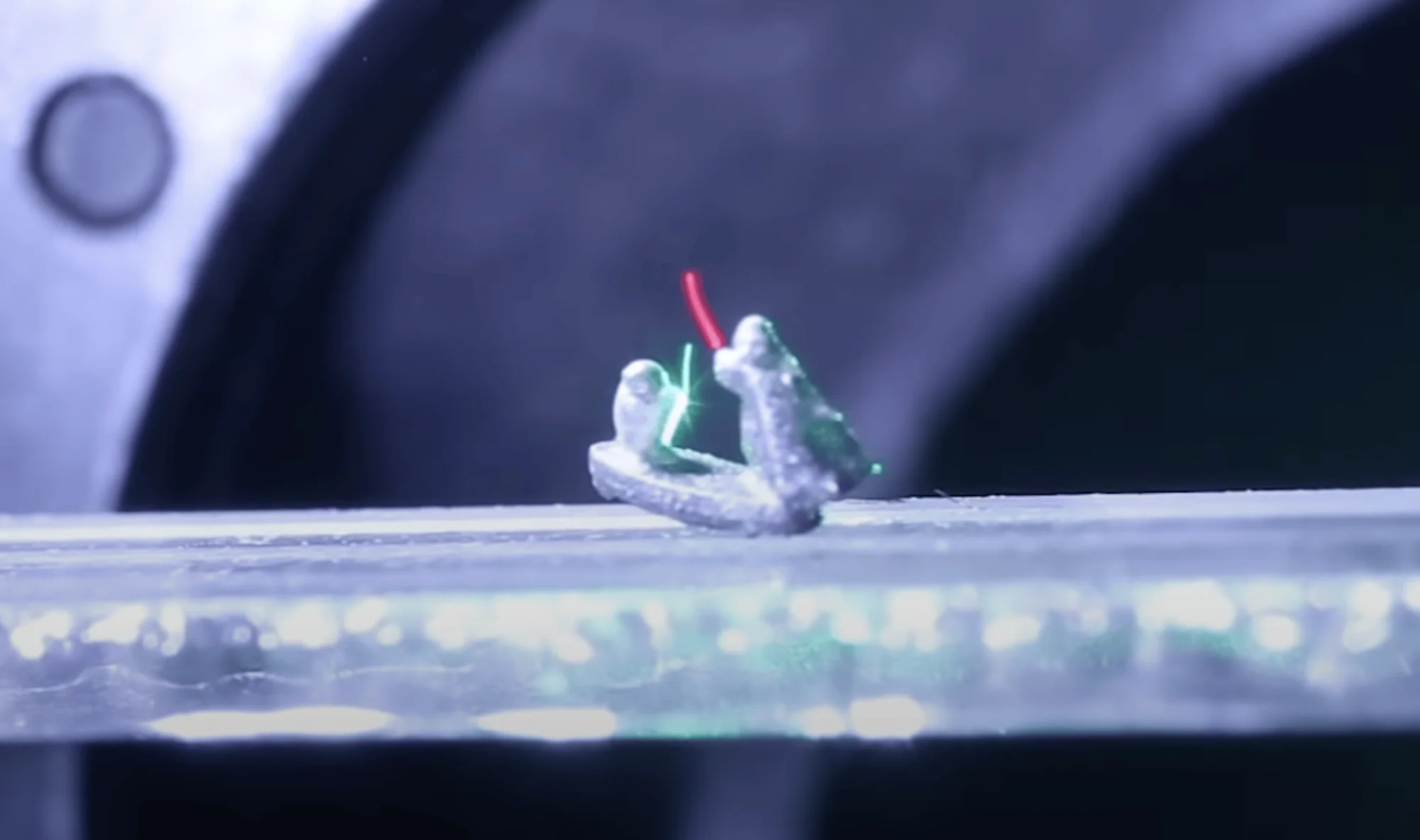 Dos miniaturas impresas en 3D de personajes con sables de luz rojo y verde enfrentándose sobre una superficie de cristal.