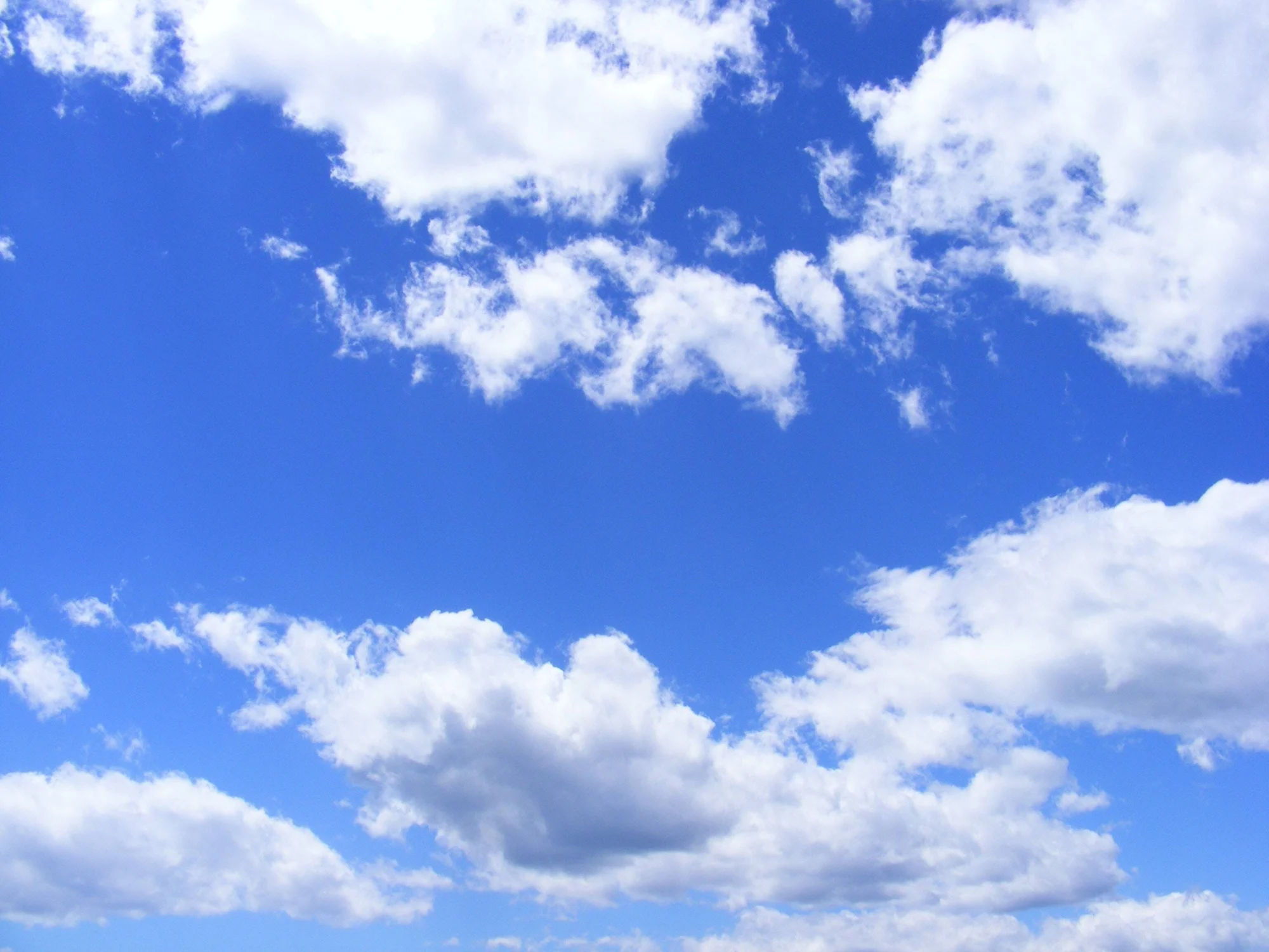 Cielo azul intenso con nubes cúmulos blancas dispersas en un día despejado.