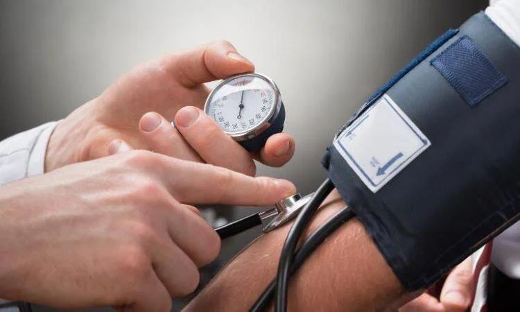 Profesional de salud toma la presión arterial a un paciente usando un tensiómetro y estetoscopio.