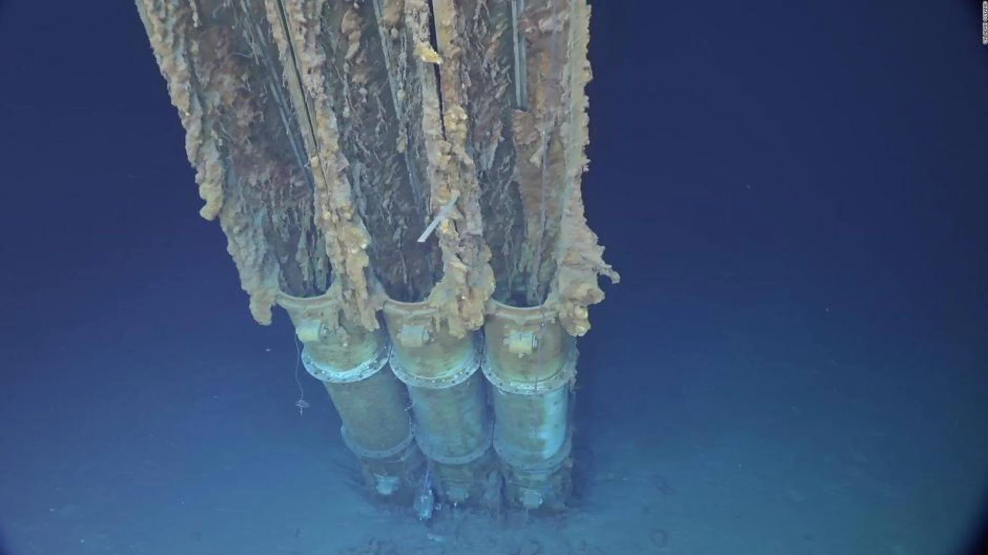 Tres hélices corroídas de un naufragio yacen en el fondo del océano, cubiertas de óxido y organismos marinos.