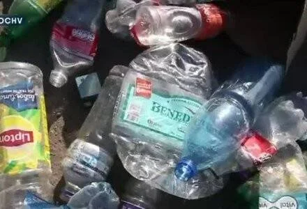 Varias botellas plásticas vacías de distintas marcas apiladas en un contenedor de reciclaje.