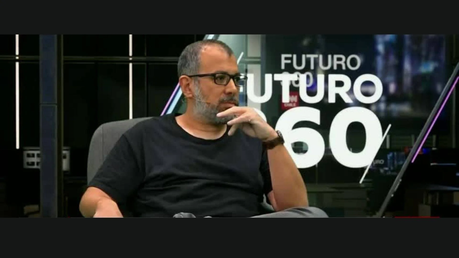 Hombre con lentes y camiseta negra sentado en estudio del programa televisivo Futuro 360.