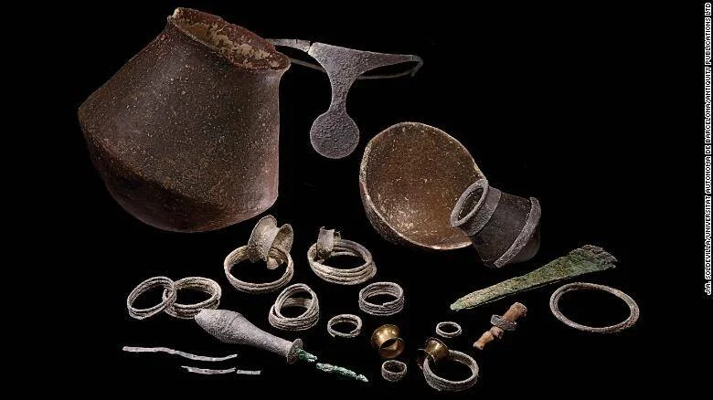 Colección de artefactos arqueológicos que incluye vasijas de cerámica, anillos, brazaletes y punta de lanza de la Edad del Bronce.