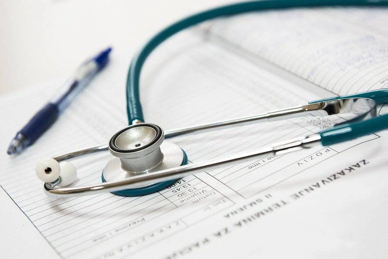 Estetoscopio verde apoyado sobre un formulario de citas médicas junto a un bolígrafo azul.