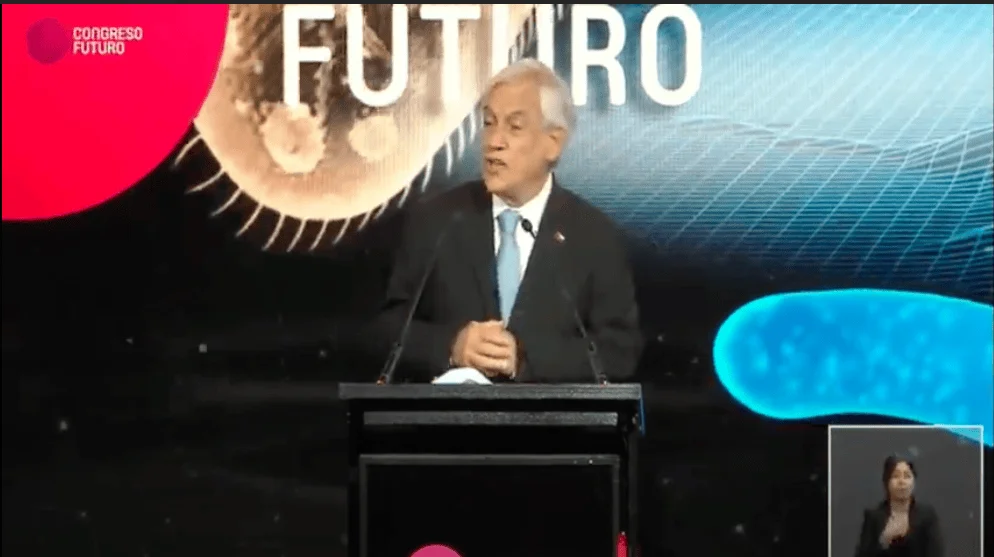 Hombre con corbata azul habla en un podio durante el evento Congreso Futuro, con intérprete de señas en pantalla.