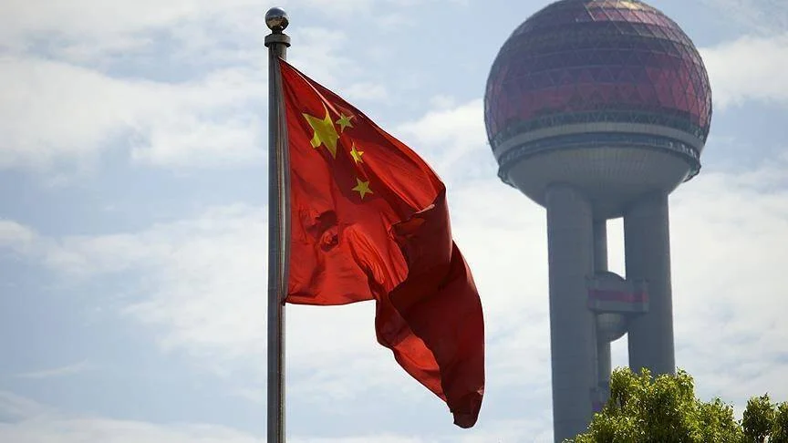 Bandera china ondeando con la Torre de la Perla Oriental de Shanghái al fondo.