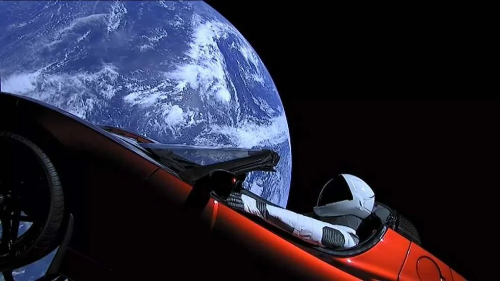 Automóvil deportivo rojo con un maniquí vestido de astronauta flota en el espacio con la Tierra de fondo.