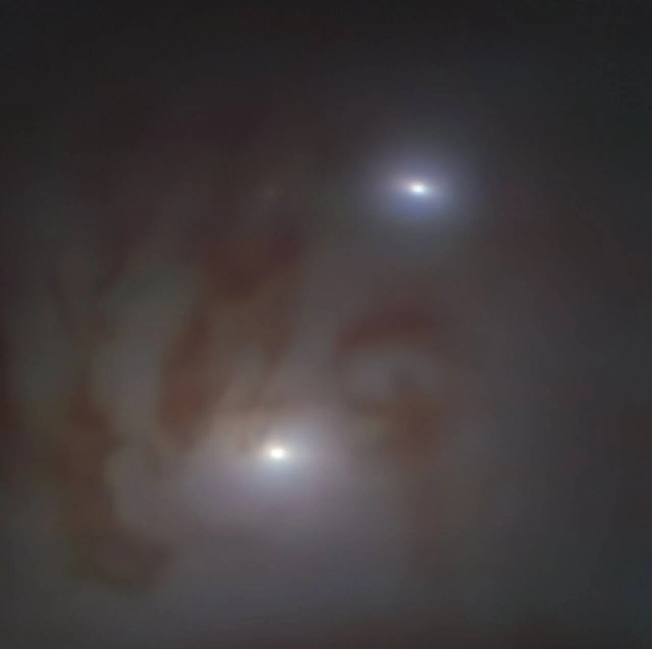 Dos núcleos activos luminosos en el centro de galaxias en proceso de fusión, rodeados de gas y polvo rojizo.