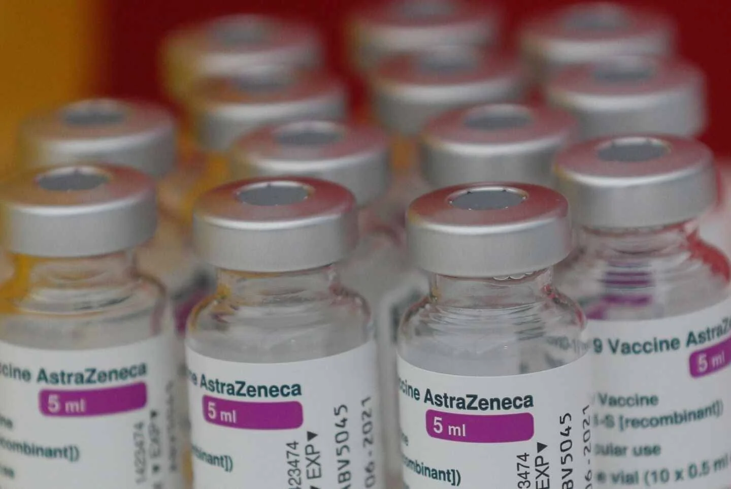 Múltiples viales de la vacuna AstraZeneca de 5 ml alineados en una bandeja roja.