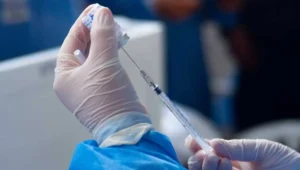Manos con guantes extraen dosis de una vacuna con una jeringa en un centro de salud.